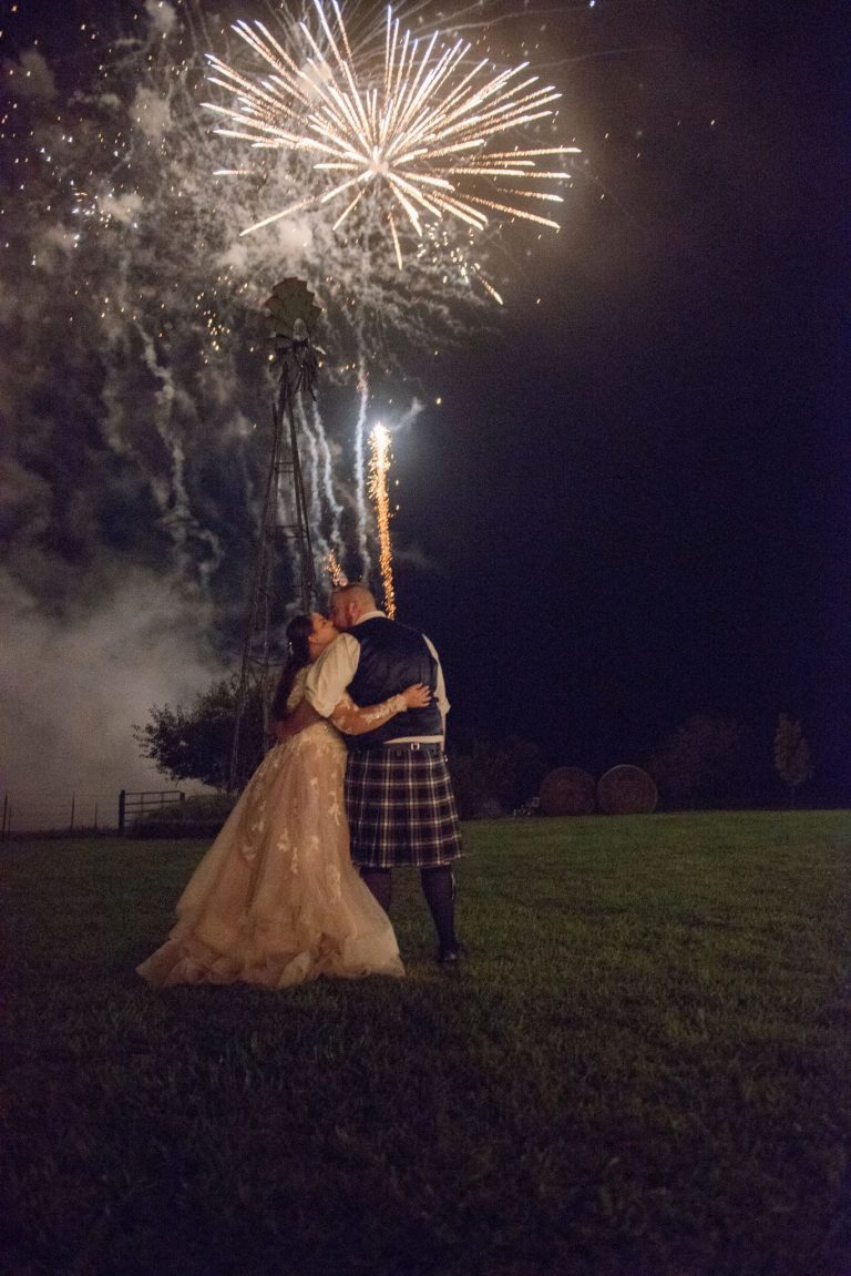 A Norman's bride and her groom share a kiss under the fireworks.