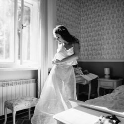 Black and white image of a bride putting on a slip undergarment