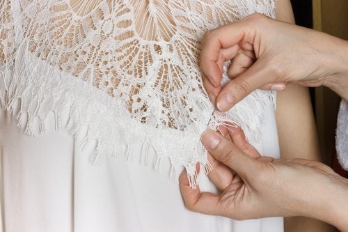 A seamstress prepares a wedding dress during a fitting.