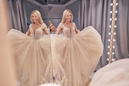 A woman looking at her appearance in a wedding dress in the mirror