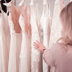 Close up of woman looking at wedding dresses hanging at a trunk show