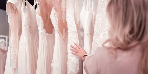 Close up of woman looking at wedding dresses hanging at a trunk show