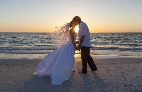 A married couple, bride and groom, kissing at sunset on a beautiful tropical beach