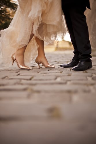 A photo of the feet of a man and woman in wedding attire.
