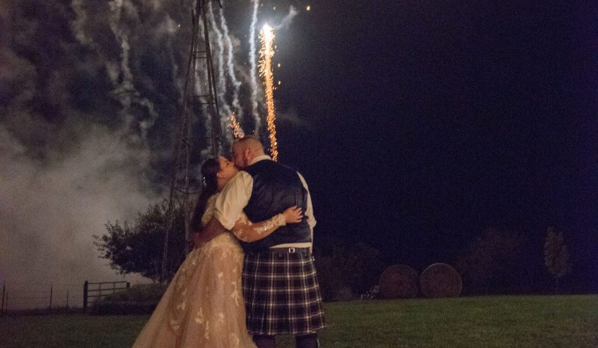 A Norman's bride and her groom share a kiss under the fireworks.